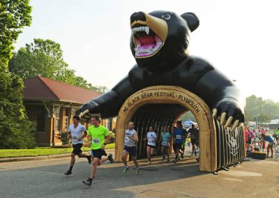 Runners emerging from a large inflatable bear tunnel at the Black Bear Festival in Plymouth.