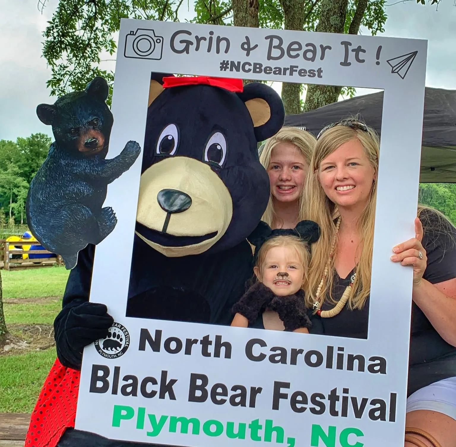 A family poses with a bear mascot in a festival photo frame at the North Carolina Black Bear Festival.